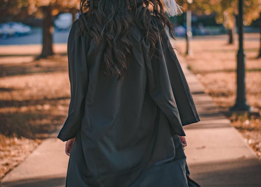 woman in black long sleeve dress standing on brown concrete pathway